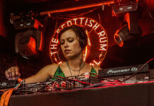 A young woman DJs against a red neon background