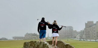 A man and a woman in slogan hoodies stand on a golf course bridge