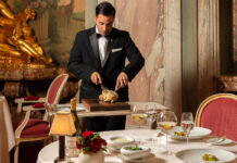 A smartly dressed waiter carves a chicken