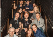 A team of cheerful hospitality trade professionals sitting on a staircase