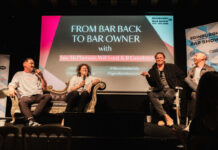 Four men sit on an informal stage having a chat