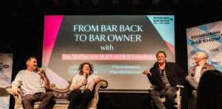 Four men sit on an informal stage having a chat