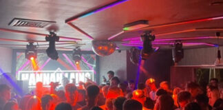 A darkly lit nightclub dance floor full of young people