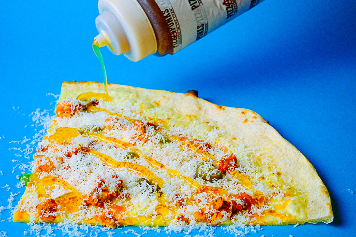 a big slice of pizza getting hot honey drizzled onto it