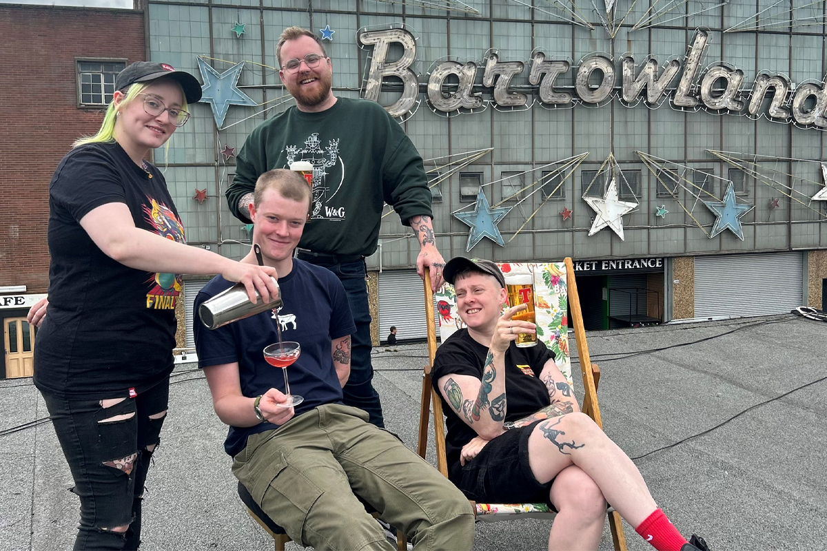 four people on the roof a bar pouring a cocktail and drinking pints of beer