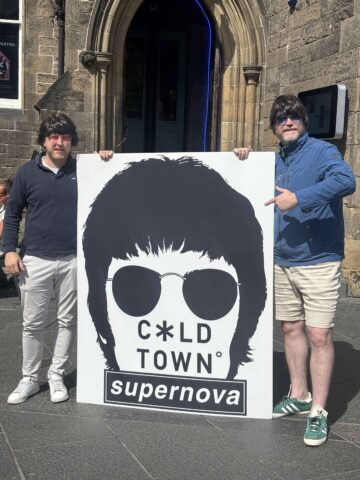 Cold Town House staff pose beside an Oasis-themed sign.