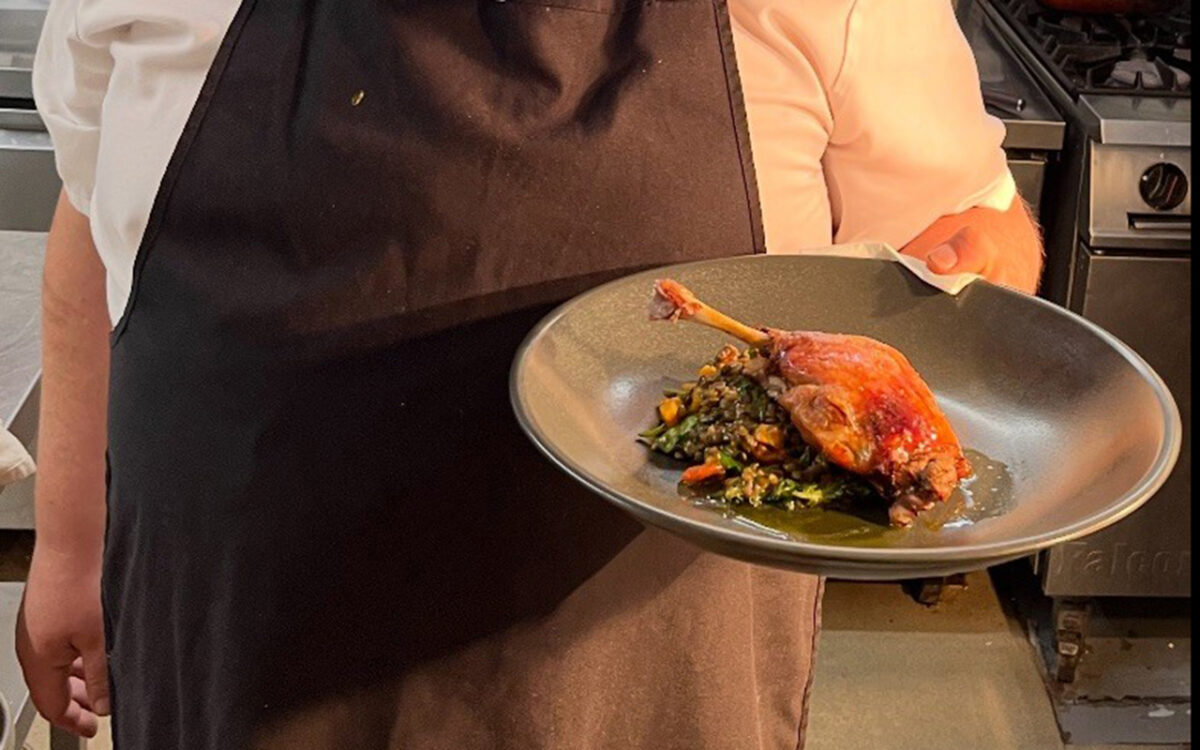 A dish of duck held by a chef.